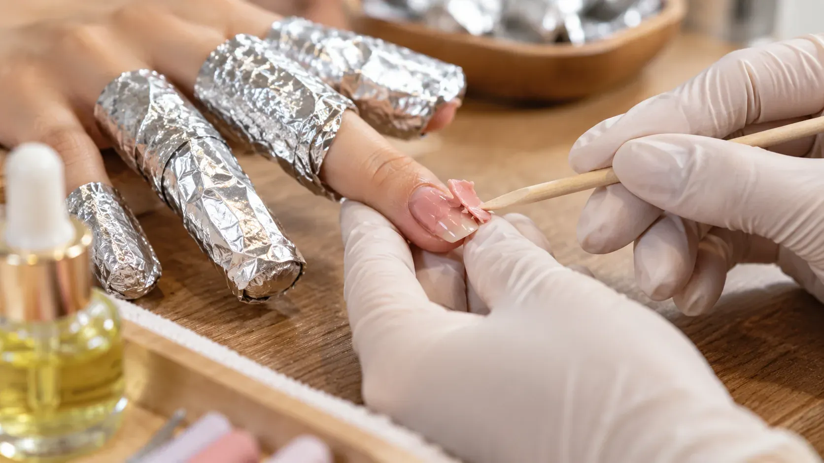 Gel polish being removed safely with foil wraps at a nail salon